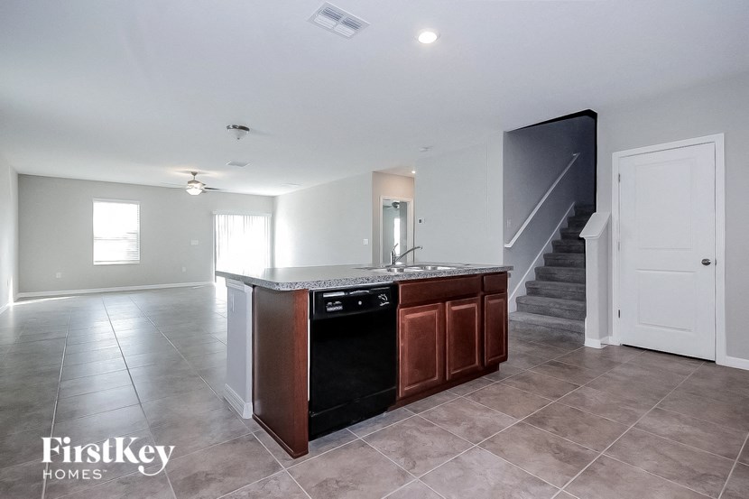 A kitchen island with a black dishwasher and a white door is in the middle of a tiled floor.
