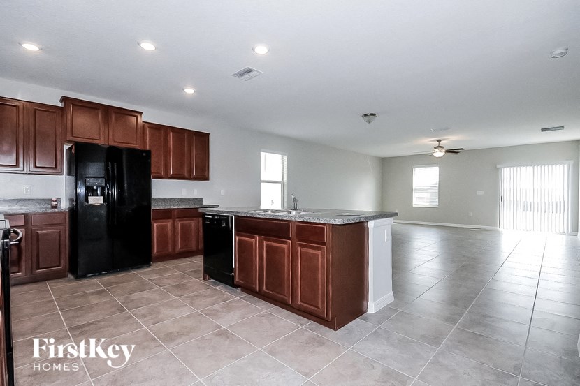 A kitchen with brown cabinets and a black fridge.