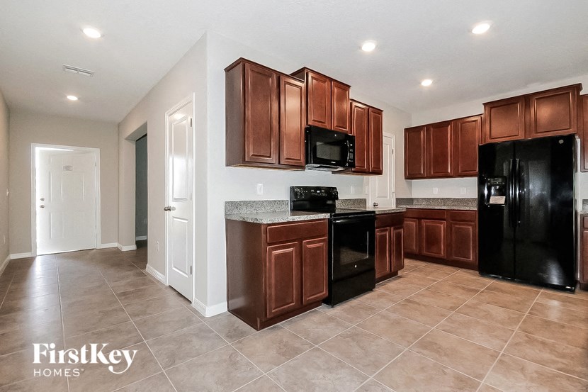 A kitchen with brown cabinets and black appliances.