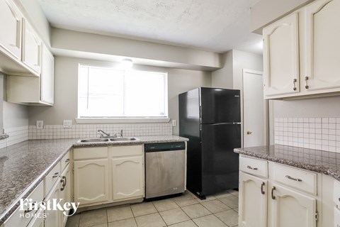 A kitchen with a black refrigerator and white cabinets.