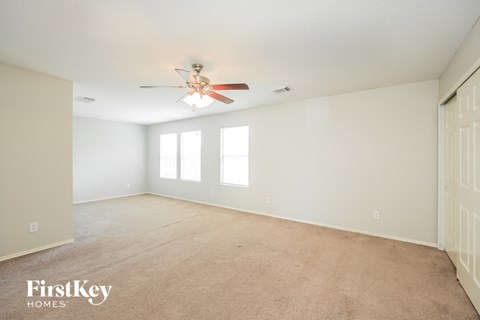 A spacious room with a ceiling fan and carpeted floor.