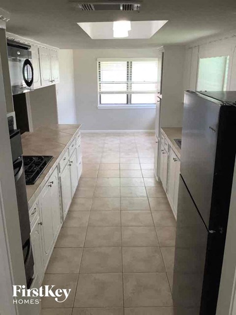 A kitchen with white cabinets and a black fridge.