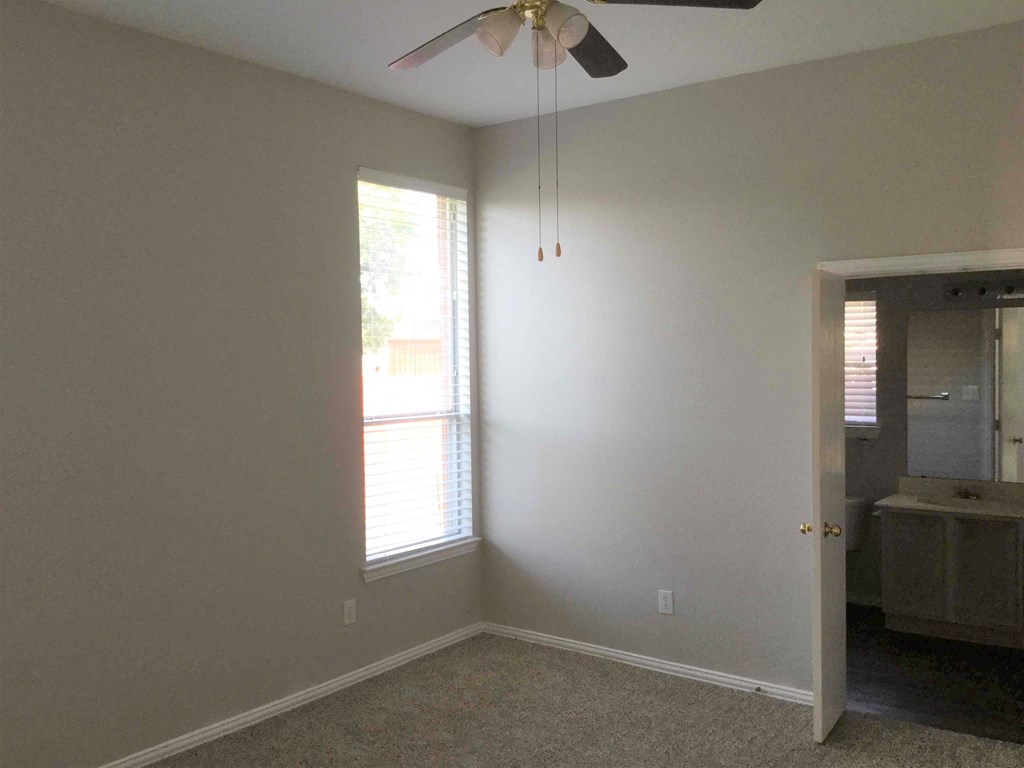 an empty room with a window and a ceiling fan