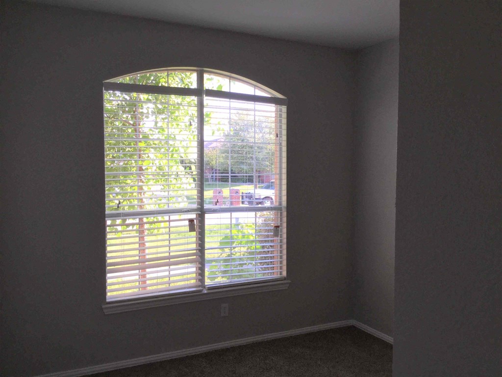 an empty room with a large window with blinds