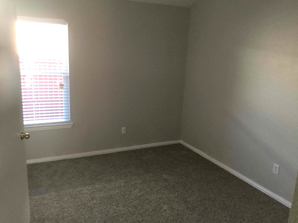 an empty room with a window and carpet