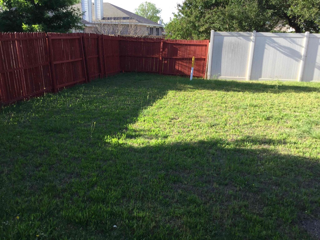 a backyard with a red fence and green grass