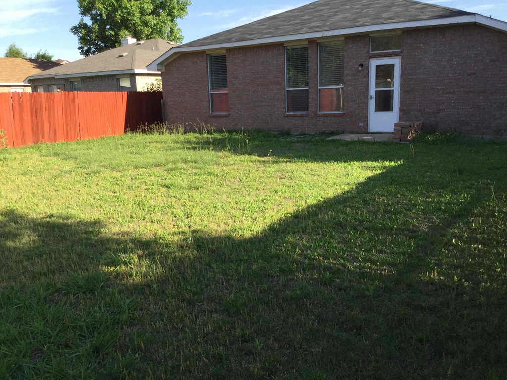 a yard in front of a brick house with a fence
