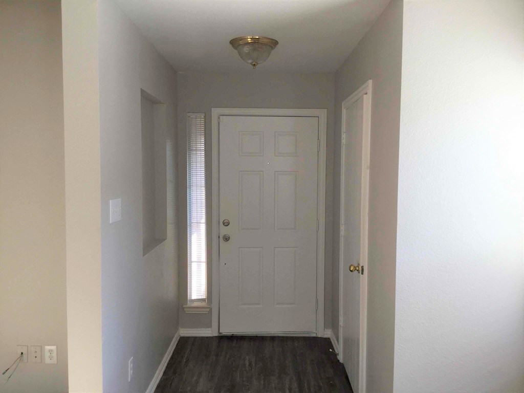 a room with a white door and a hallway with a window and a door way