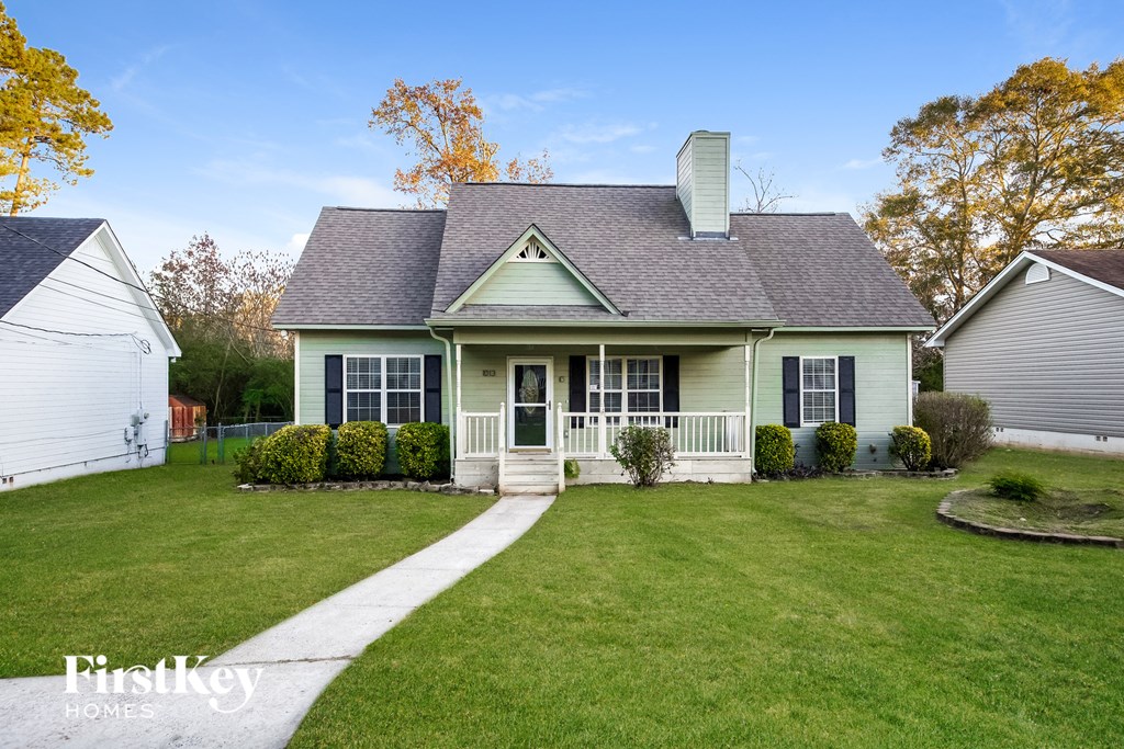 A house with a green front yard and a white fence.