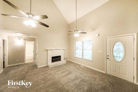 A spacious room with a fireplace and a ceiling fan.