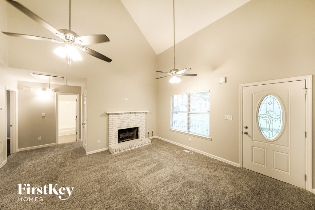 A spacious room with a fireplace and a ceiling fan.