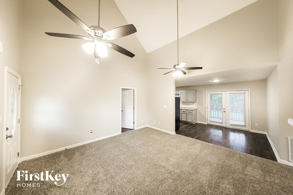 A spacious room with a ceiling fan and carpeted floor.