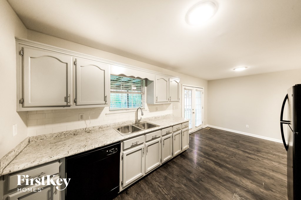 A kitchen with a granite countertop and a black refrigerator.