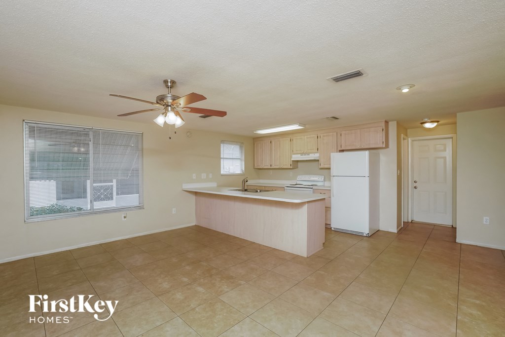 A kitchen with a fan on the ceiling and a refrigerator.