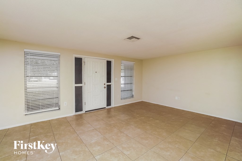 A room with a tile floor and a door leading to another room.
