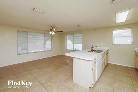 A kitchen with a white counter and a fan on the ceiling.