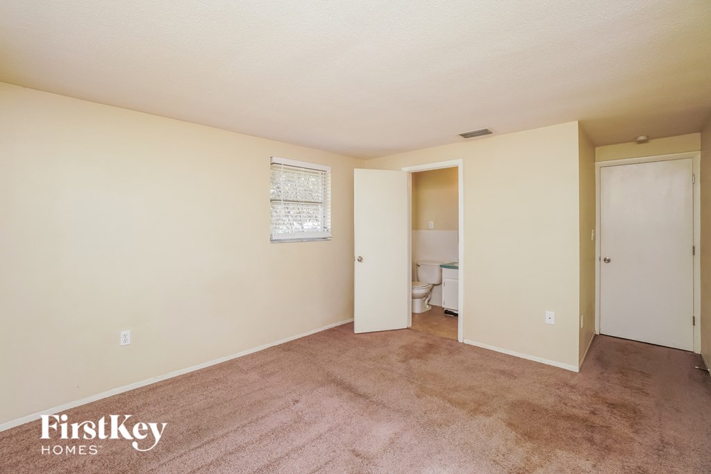 A bedroom with a carpeted floor and a window.