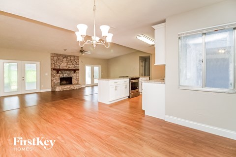 A large open living room with wood floors and a chandelier.
