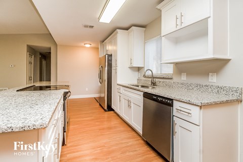 A kitchen with white cabinets and a granite countertop.
