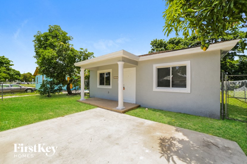 a small white house with a yard and a driveway