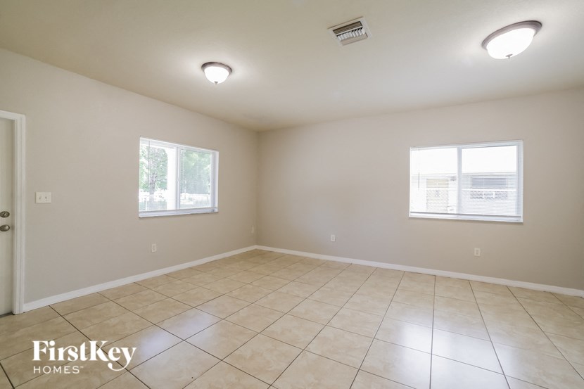 a empty living room with tiled floors and two windows