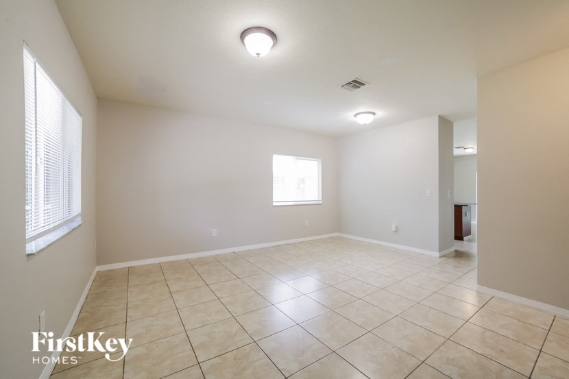 an empty living room with tiled floors and a window
