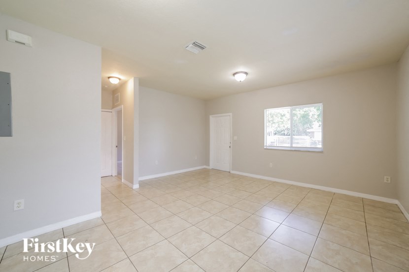 a spacious living room with tile flooring and white walls