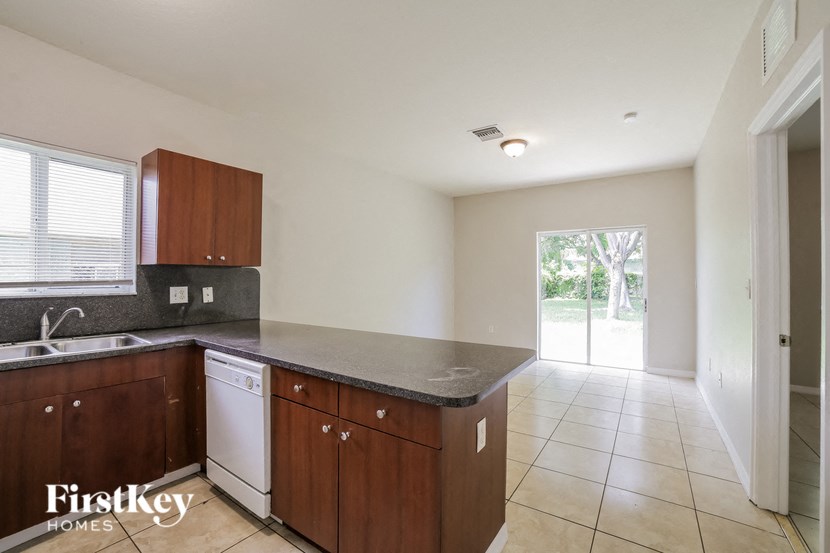 a kitchen with wooden cabinets and a sink and a door to a yard