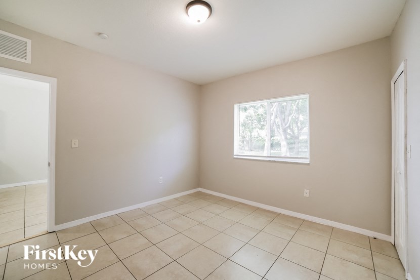 a empty living room with a window and a tiled floor