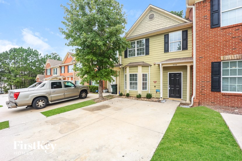 a yellow house with a driveway and a car parked in front of it