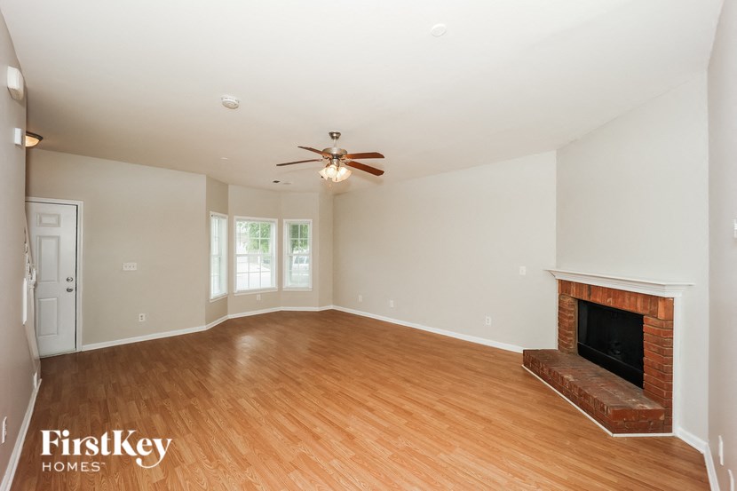 an empty living room with a fireplace and a ceiling fan