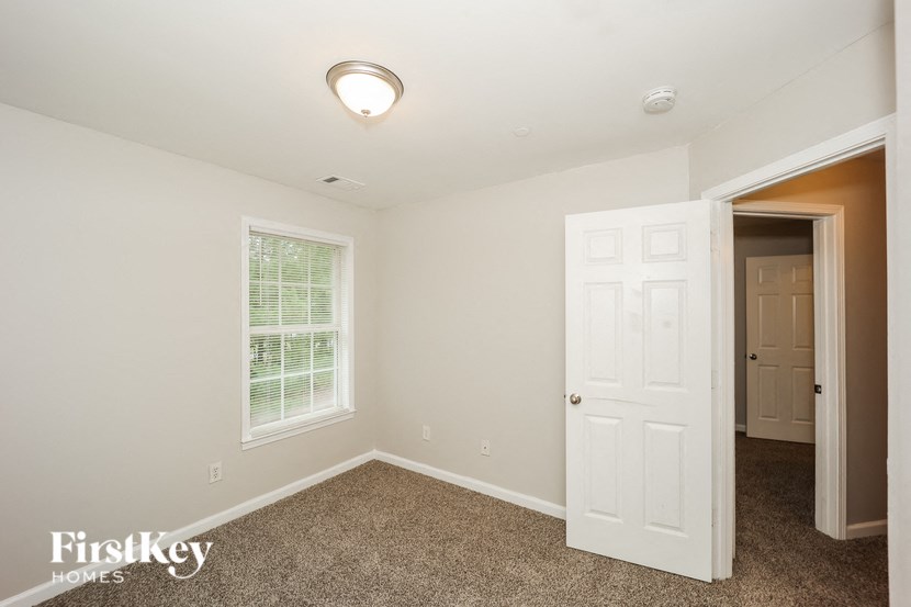 the bedroom of a home with a white door and carpet