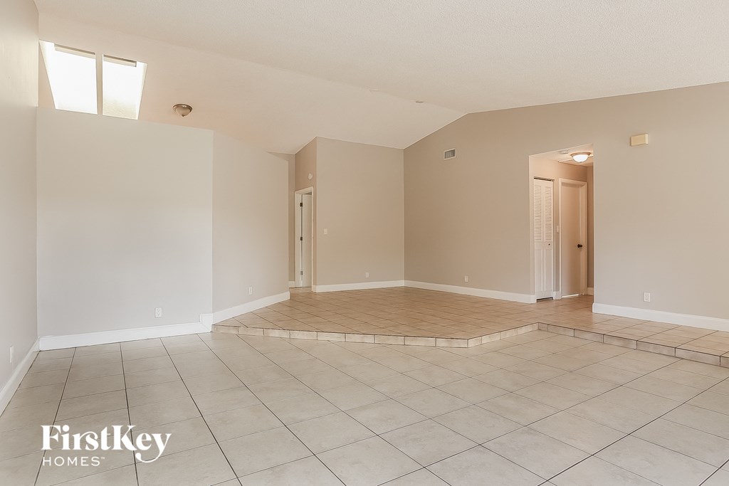 A spacious empty room with a tiled floor and a FirstKey Homes logo.