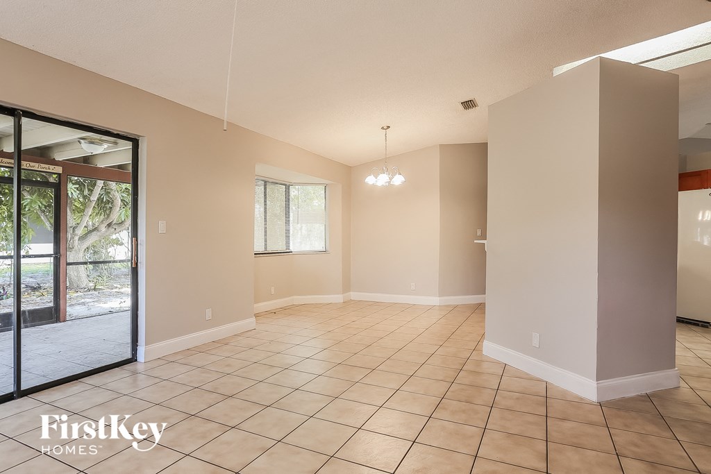 A spacious room with tiled flooring and a sliding glass door leading to a patio.