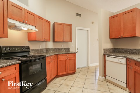 A kitchen with orange cabinets and a black stove top oven.
