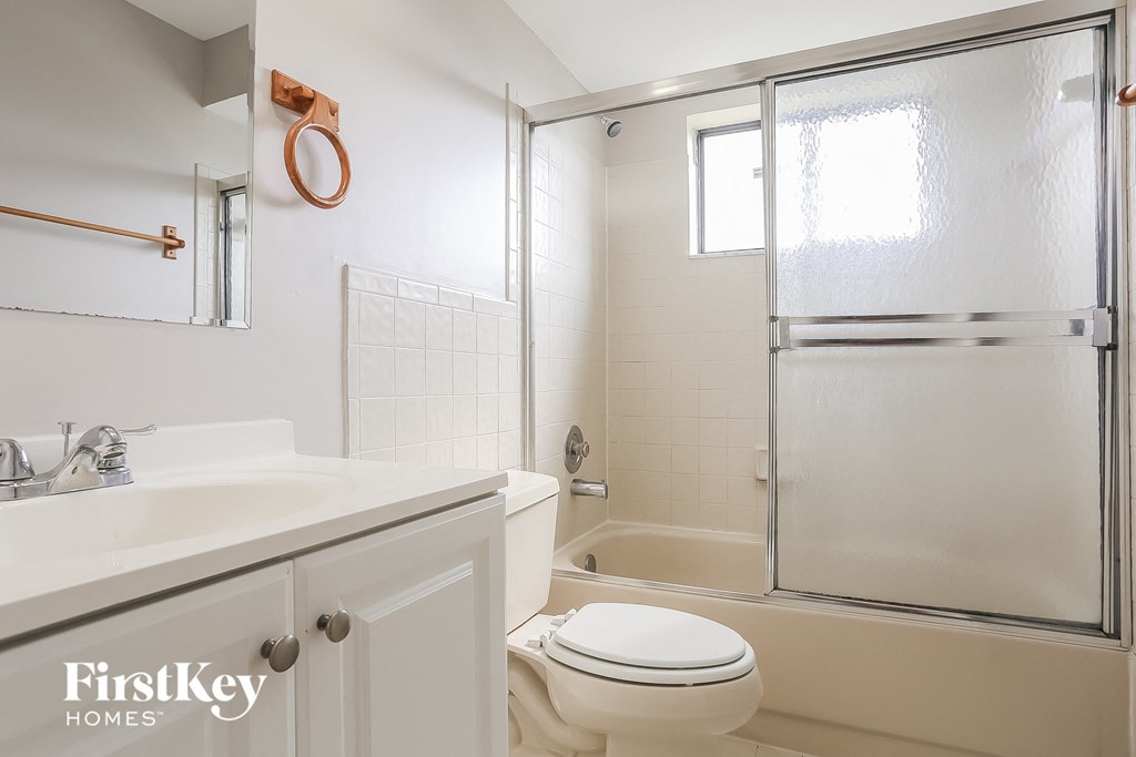 A bathroom with a toilet, sink, and shower.