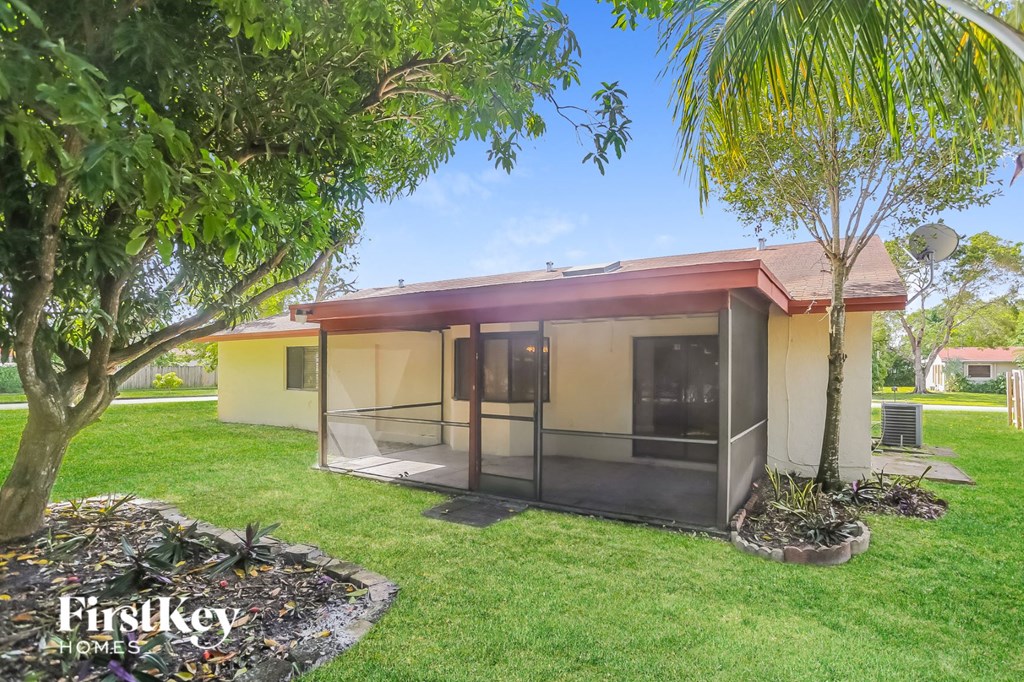 A house with a red roof and a glass door is surrounded by greenery.
