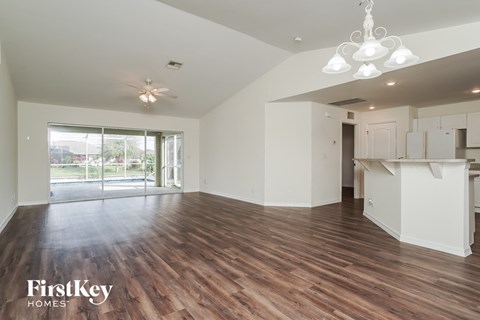 an empty living room with a kitchen and a sliding glass door
