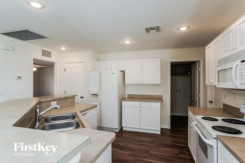 a kitchen with white cabinets and white appliances and white counter tops