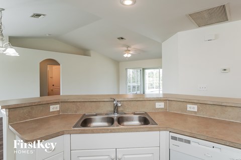 a kitchen with white cabinets and a sink and a window