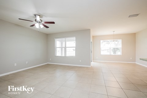 A spacious room with a ceiling fan and two windows.
