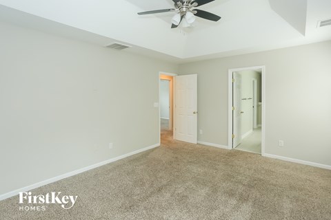 a carpeted living room with a ceiling fan