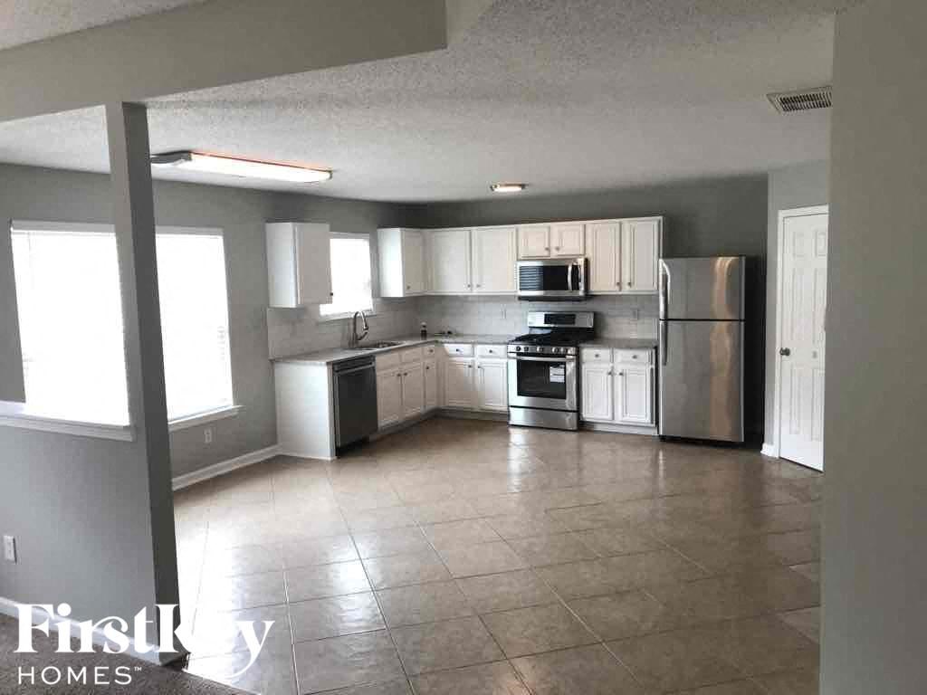 an empty kitchen with stainless steel appliances and white cabinets