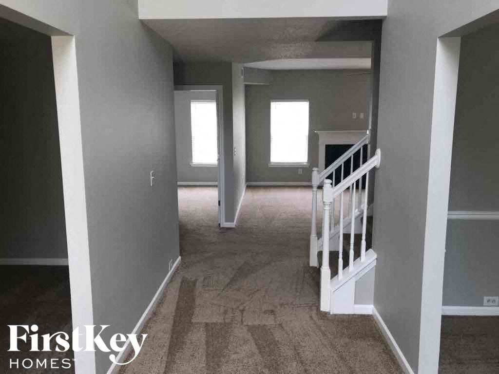 a empty house with a staircase and a hallway with grey walls