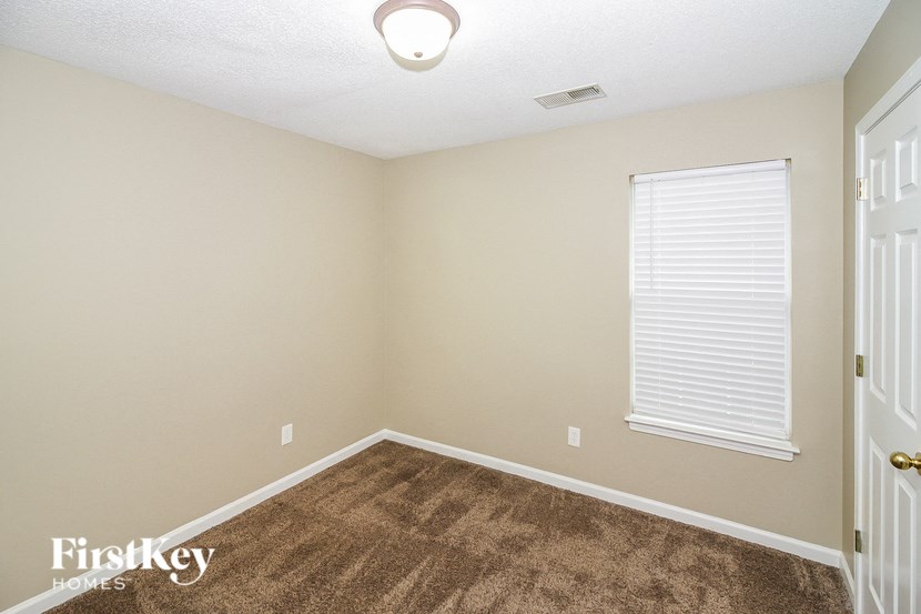 an empty room with a large window and a brown carpet