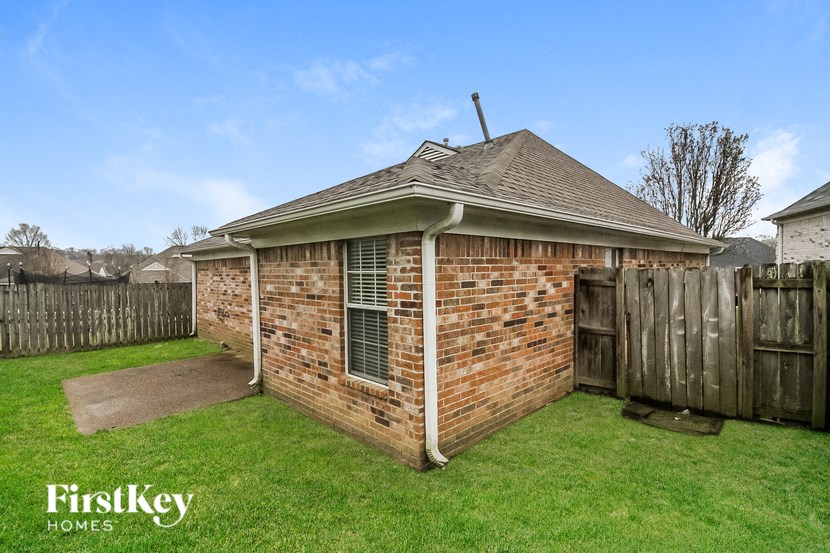 the backyard of a brick house with a wooden fence