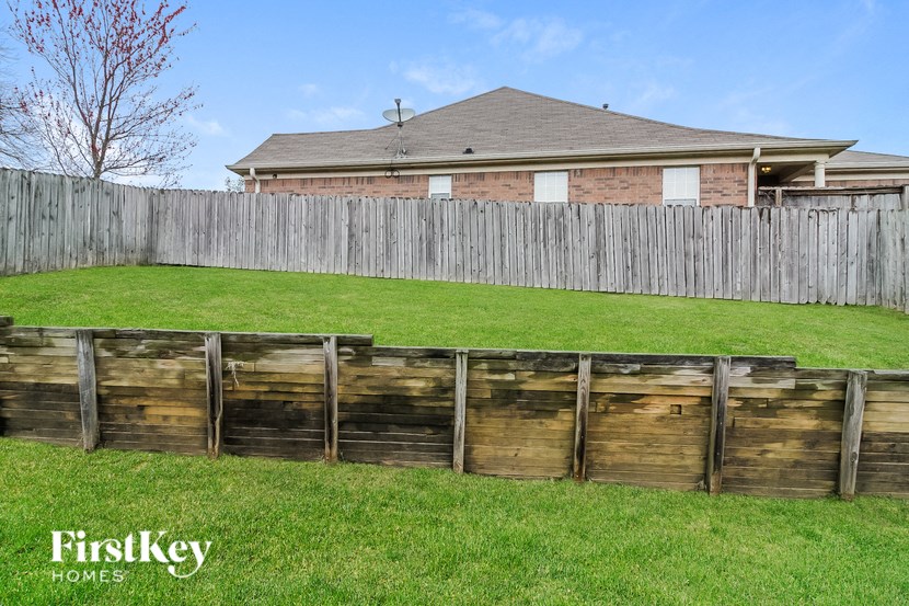 a yard with a wooden fence and a house behind it