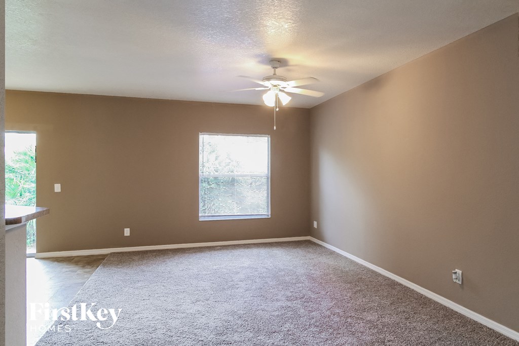 an empty living room with a ceiling fan and a window