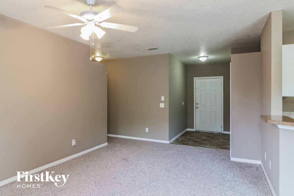 a empty living room with a ceiling fan and a white door