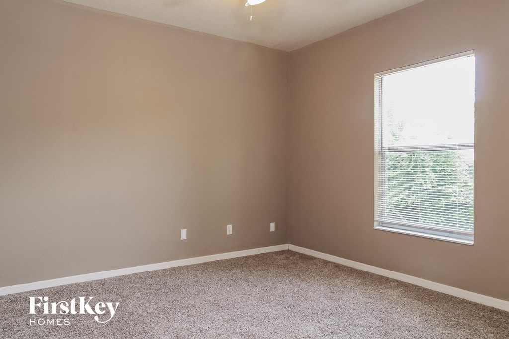 a bedroom with a window and a carpeted floor